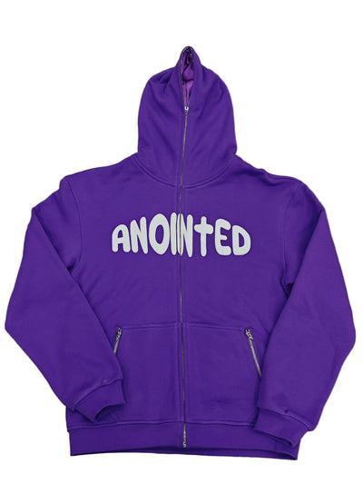 Purple full-zip hoodie with a large 'ANOINTED' text in the centre of the upper torso. Hoodie contains a purple satin fabric inside the hood and the hoodie has a custom cross zipper. There are exposed zippers on the pockets.